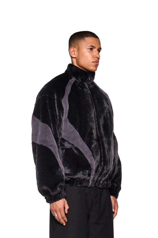 Mann trägt Two-Toned Fur Jacket Black mit Stehkragen und farbigen Einsätzen, Raglanärmeln, Reißverschluss und Eingriffstaschen, präsentiert von OLAKALA.