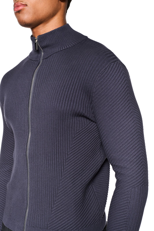 Nahaufnahme eines Mannes, der die CI Slim Knit Jacket Gray trägt. Sichtbar sind feine Strickmuster, ein Reißverschluss und eine schmale Passform.