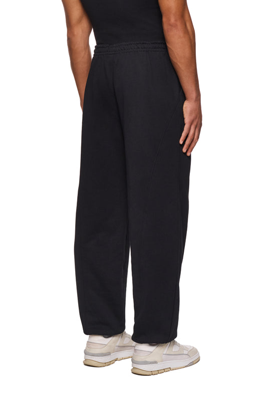 Person trägt CC Core Sweatpants Black: schwarze Jogginghose aus strapazierfähiger Mischfaser, elastischer Bund mit Kordelzug, Rippbündchen und Teilungsnähte für eleganten Look.