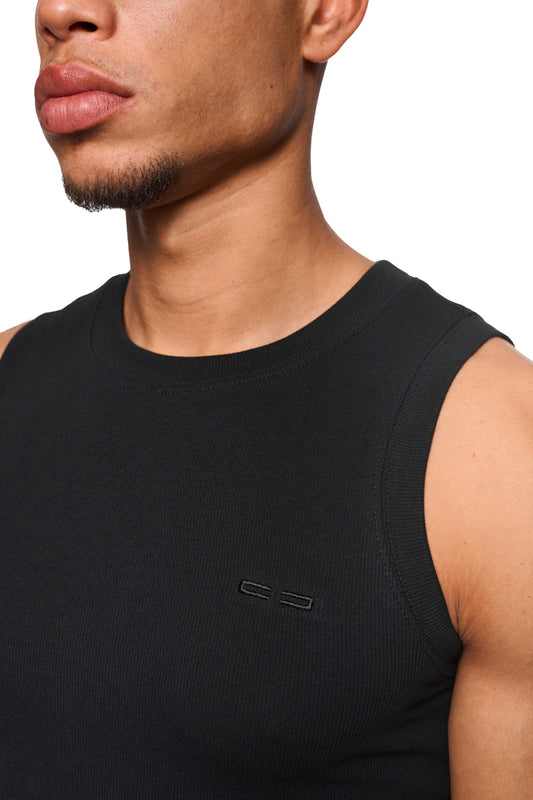 Nahaufnahme eines Mannes, der das CC Core Tanktop Black trägt, mit gesticktem OLAKALA-Icon auf der linken Brust, enger Passform und elastischem Ripp-Stoff.