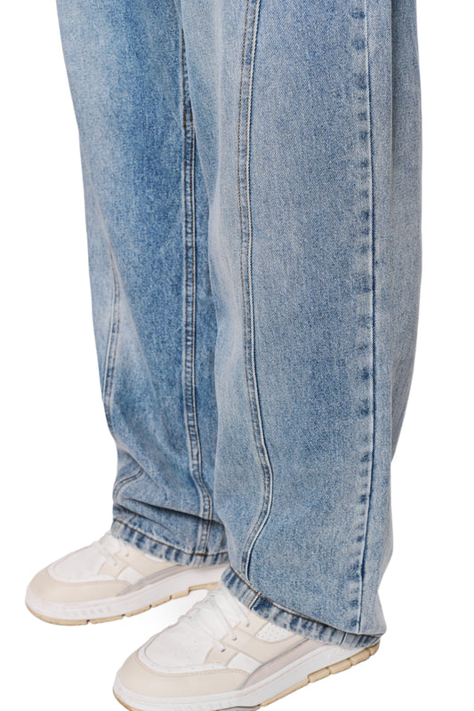 Nahaufnahme der CC Core Denim Pants Blue, robustes Denim mit 5-Pocket-Design, abgenähter Gesäßtasche und OLAKALA PU-Patch, kombiniert mit weißen Sneakers.