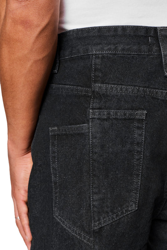 Nahaufnahme der CC Core Denim Pants Black mit robustem Denim-Gewebe und 5-Pocket-Style, einschließlich abgenähter linker Gesäßtasche und OLAKALA PU-Patch am Bund.
