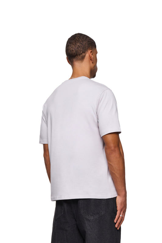 Mann in weißem CC Core T-Shirt mit OLAKALA-Logo auf Brust, reguläre Passform, unisex, zeigt Rückseite und Detailansicht von Hose und Hand.