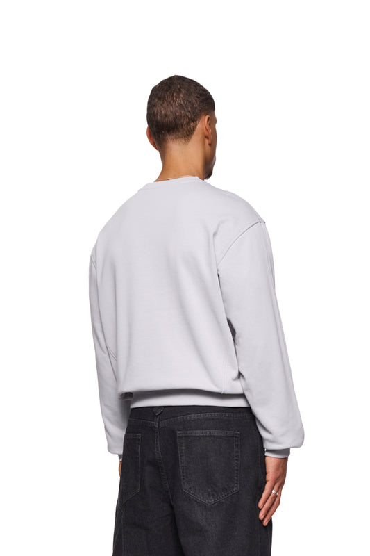 Mann im CC Core Sweater Grau, zeigt strapazierfähiges Design mit Rippbündchen und verlegten Nähten für Komfort, unisex, reguläre Passform.