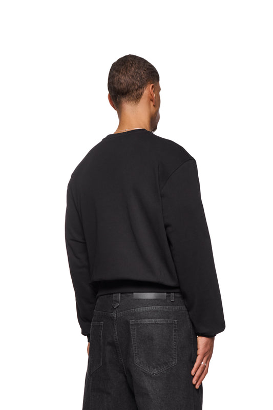 Mann von hinten im CC Core Sweater Black mit Rippbündchen und verlegten Nähten, Fokus auf Komfort und Langlebigkeit.