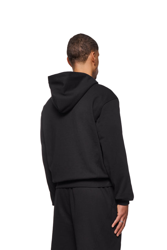 CC Core Hoodie Black aus strapazierfähiger Mischfaser mit verlegten Nähten, Rippbündchen und Kängurutasche, getragen von einer Person.