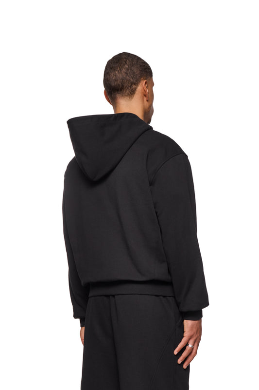 Rückansicht eines Mannes im CC Core Zip Hoodie Black mit Rippbündchen und Kängurutasche, Fokus auf Tragekomfort und Langlebigkeit.