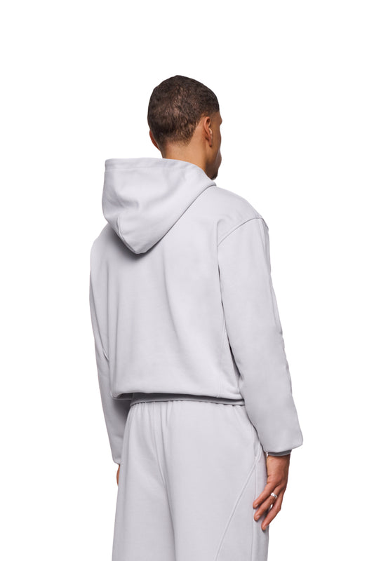 Mann in weißem CC Core Hoodie mit Kängurutasche und Rippbündchen, zeigt strapazierfähige, komfortable Passform. Unisex-Design, präsentiert von OLAKALA.