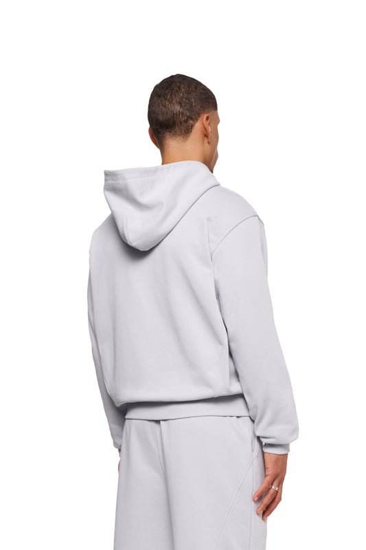 Mann trägt CC Core Zip Hoodie Gray mit Kängurutasche und Rippbündchen, bekannt für Komfort und Langlebigkeit, erhältlich im offiziellen OLAKALA® Onlineshop.
