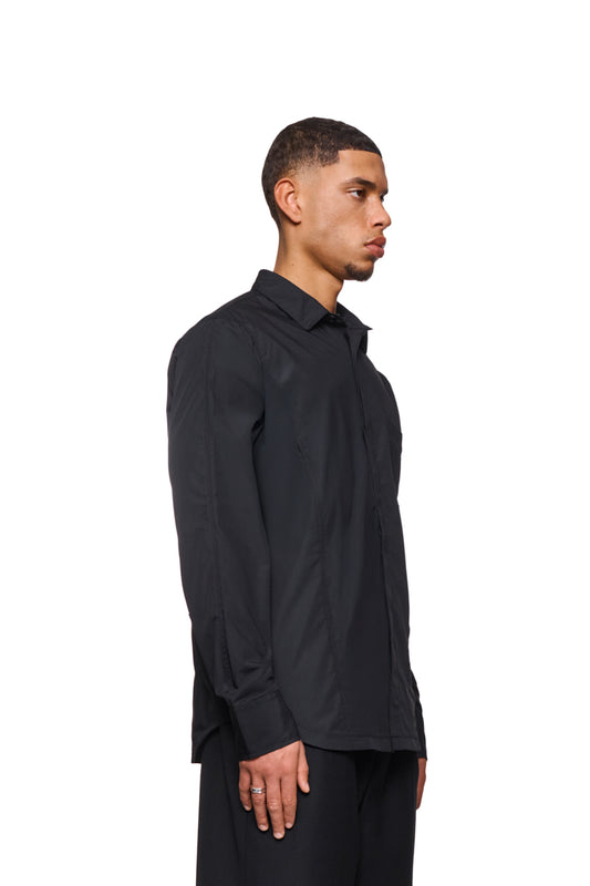 Mann in einem schwarzen CC Core Button Shirt mit Brusttasche und verdeckter Knopfleiste, zeigt die Strapazierfähigkeit und den Komfort des OLAKALA® Sortiments.