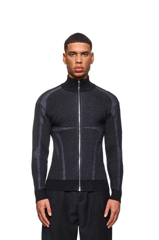 A man wears a Luminous Zip Jacket Black with a high collar and knitted pattern. The jacket has elasticated cuffs and a regular fit.