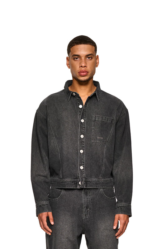 Close-up of a man wearing the 0asis Denim Overshirt Black, showing details such as the button placket, chest pockets and OLAKALA patch on the back.