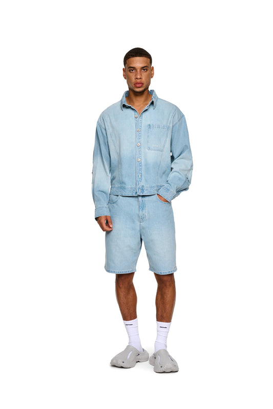 Nahaufnahme von 0asis Denim Shorts Blue mit OLAKALA-Jeansknopf und Logo-Stickerei, getragen von einer Person mit weißen Socken.
