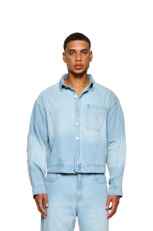 Close-up of a man wearing a 0asis Denim Overshirt Blue, with visible button placket and patch breast pocket with logo embroidery.