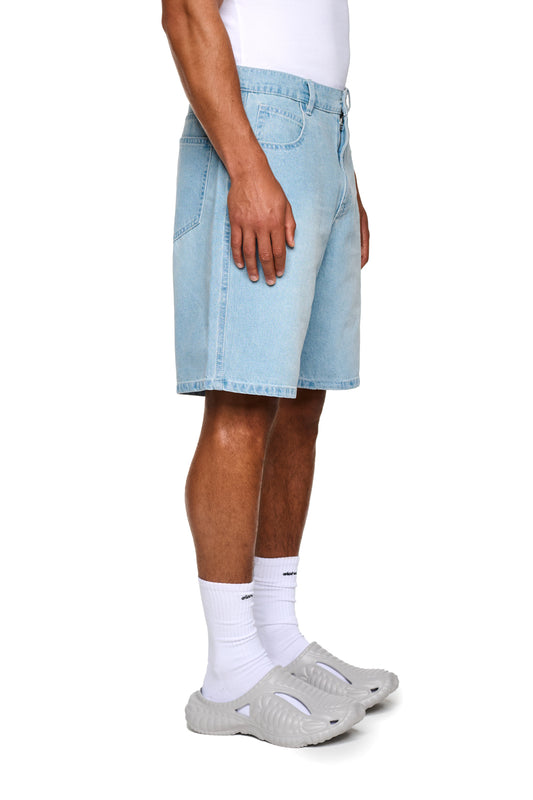 Nahaufnahme eines Beins, das Oasis Denim Shorts Blue mit geprägtem OLAKALA Patch und Logo-Stickerei trägt, betont die reguläre Passform und unisex Design.