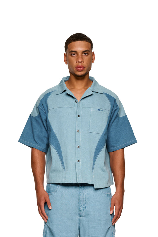 Nahaufnahme des Echoes Denim Icon Shirt Blue mit kubanischem Kragen, Knopfleiste, aufgesetzter Brusttasche und Logo-Stickerei, dargestellt auf einem Mann.