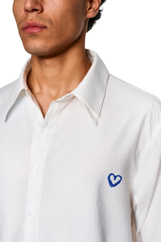 Nahaufnahme eines Mannes mit dem Crayon Summer Shirt Heart, das eine zerknitterte Oberfläche und eine Herz-Grafik auf der linken Brust zeigt, ideal für heiße Sommertage.