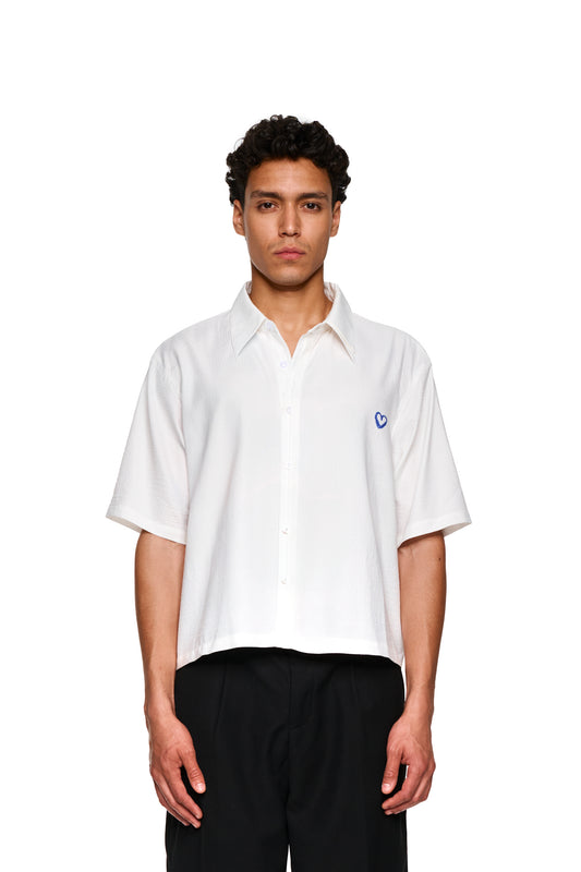 Nahaufnahme eines Mannes mit dem Crayon Summer Shirt Heart: kubanischer Kragen, Herz-Grafik auf der Brust, luftiger Stoff, perfekt für heiße Sommertage.
