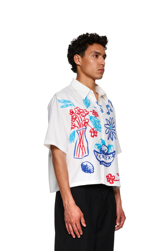 Nahaufnahme eines Crayon Summer Shirt Graphic mit floralem Design auf einem Ärmel, getragen von einer Person. Ideal für lässige Anlässe im OLAKALA® Onlineshop.