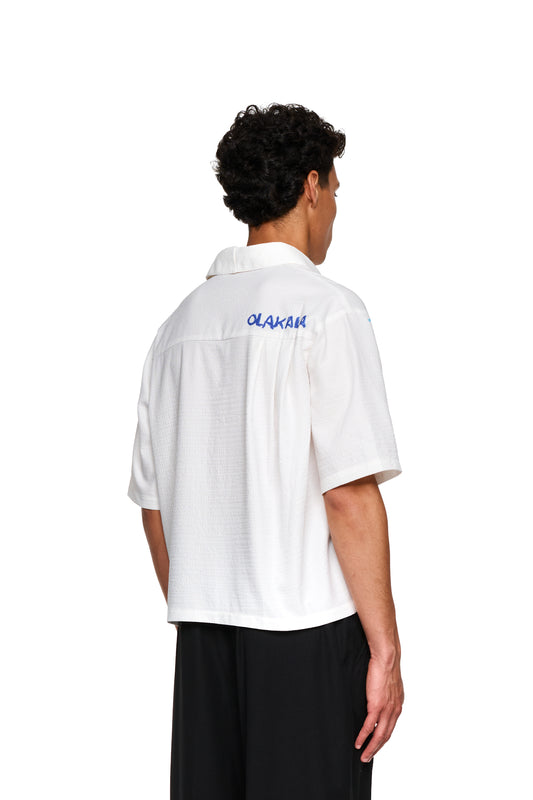 Nahaufnahme eines Mannes im weißen Crayon Summer Shirt Graphic, betont klare Linien und Grafikdesign, präsentiert von OLAKALA® Onlineshop.