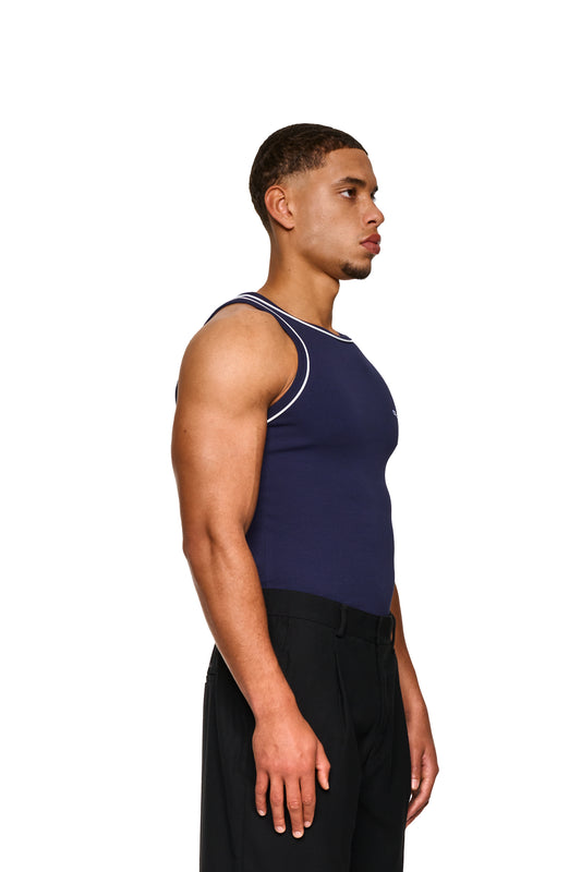 Nahaufnahme eines Mannes, der das Contrast Tanktop Navy Blue trägt, mit elastischem Ripp-Stoff und gesticktem OLAKALA-Icon auf der linken Brust.
