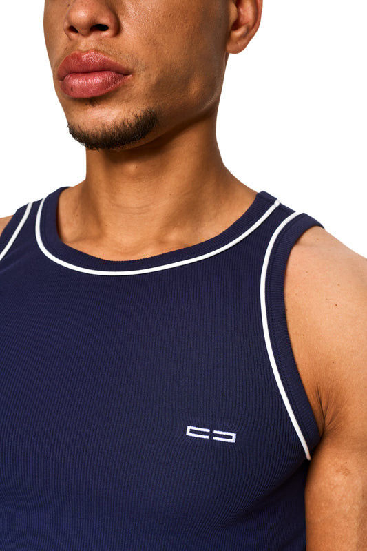 Nahaufnahme eines Mannes, der ein eng anliegendes, elastisches Contrast Tanktop Navy Blue mit kontrastfarbigen Paspeln und gesticktem OLAKALA Icon auf der Brust trägt.