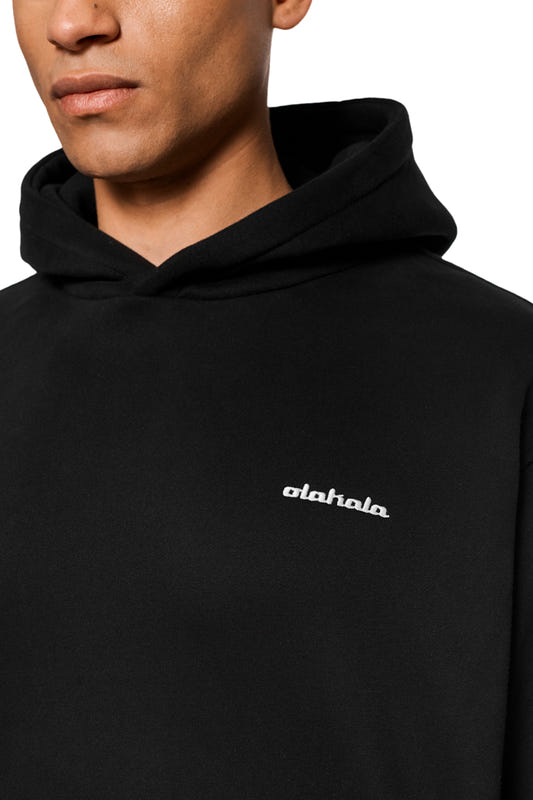 Close-up of a black hoodie with a small white logo on the chest, worn by a man.