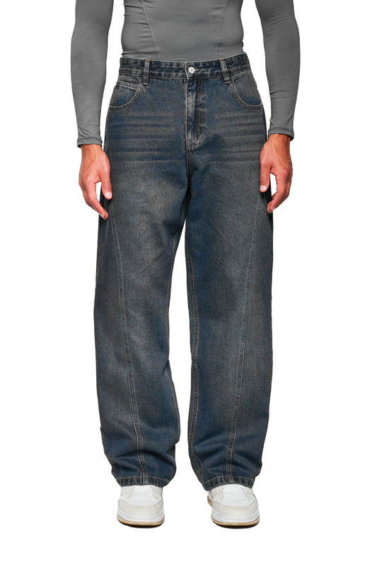 CC Core Denim Pants Tinted Indio: Locker sitzende Jeans mit elastischem Knöchelbund, klassischem 5-Pocket-Stil und subtiler Hüft-Verwaschung, kombiniert mit weißen Sneakern und grauem Top.
