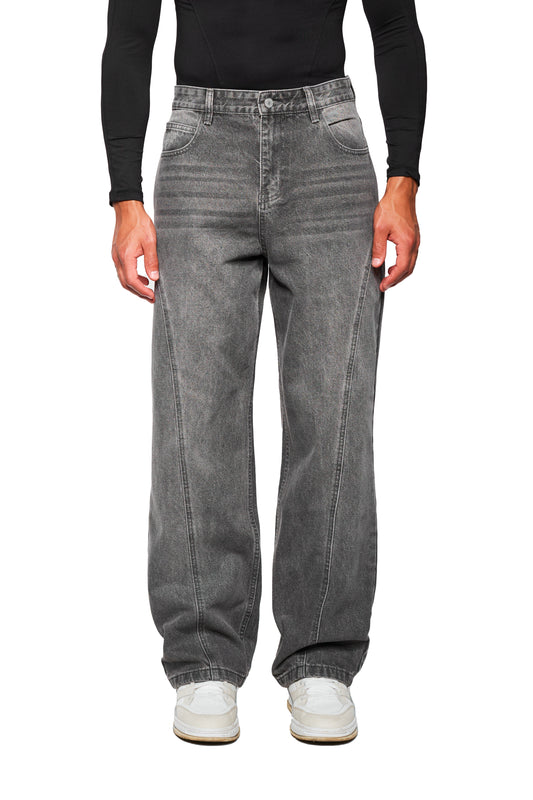 Person trägt die CC Core Denim Pants Washed Gray, locker sitzende, verwaschene Jeans mit asymmetrischer Gesäßtasche, vertikaler Naht und weißen Sneakers.