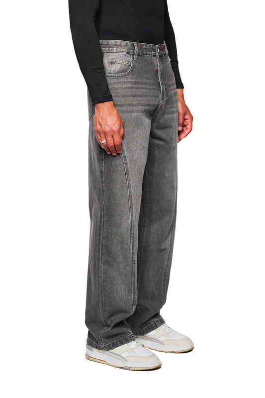 Person trägt CC Core Denim Pants Washed Gray mit weitem Bein, kombiniert mit weißen Sneakers. Silberner Ring an der linken Hand. Ideal für vielseitigen, modernen Look.