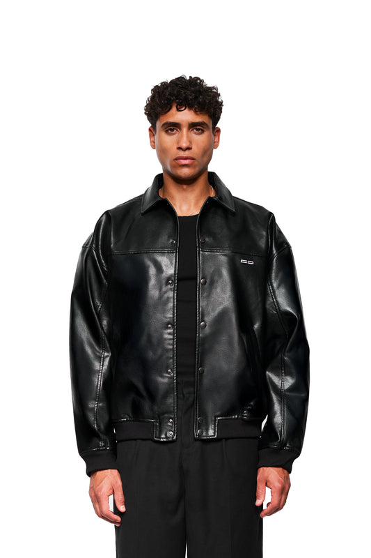 Männliches Model trägt die CC Leather Jacket Icon Black aus veganem Lederimitat mit gesticktem OLAKALA-Icon und Druckknopf-Leistentaschen vor weißem Hintergrund.