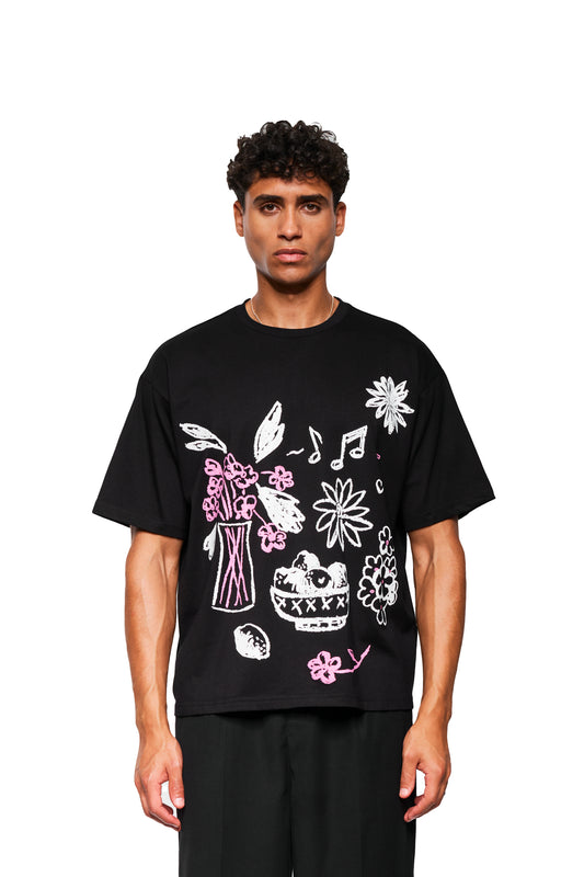 Männliches Modell im Crayon T-Shirt Oversized Black mit skizzenhaften Blumen- und Fruchtmotiven vorne, lockere Passform, Unisex, präsentiert von OLAKALA.