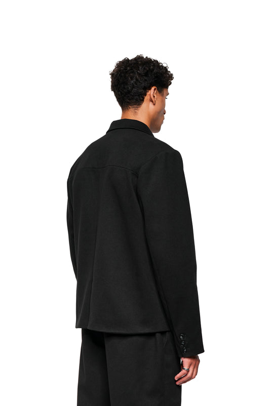 Person from behind in an Exquisite Blazer Black with asymmetrical lapel, tight two-seam sleeves and walking slit, worn by OLAKALA® online store model.