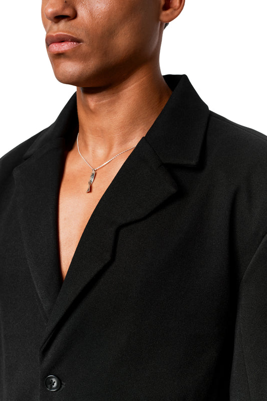 Person wears the Exquisite Blazer Black with asymmetric lapel and silver chain, showing tight fit and elegant design.