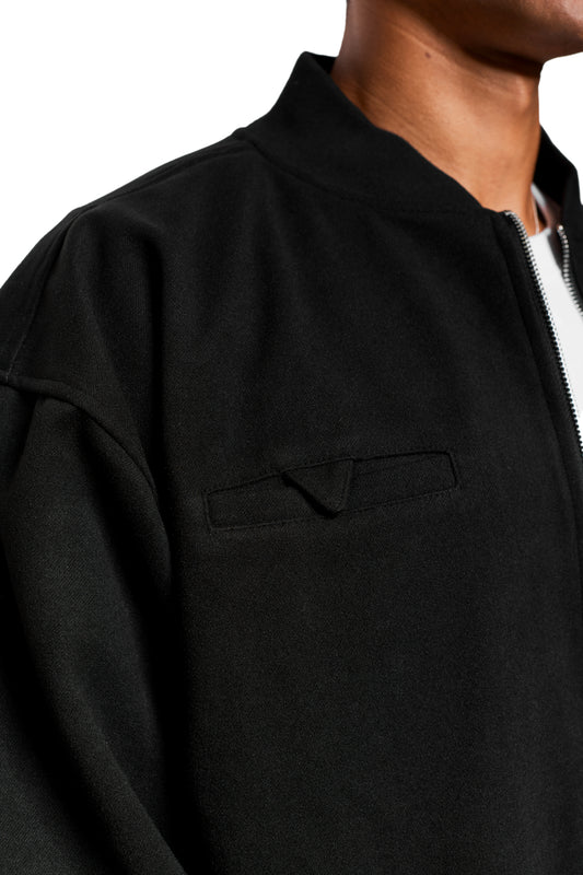 Person wearing Exquisite Bomber Jacket Black: black zipper, ribbed stand-up collar, chest pocket, loose fit, embroidered OLAKALA icon visible.
