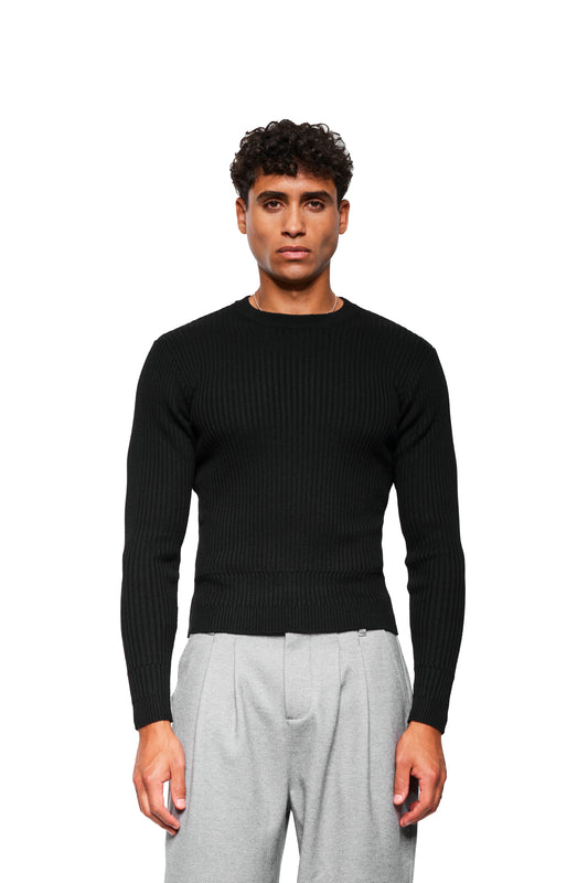 Mann trägt Exquisite Knit Longsleeve Black, eng anliegendes, langärmeliges Rippenstrick-Oberteil mit gestricktem Bund und Ärmelbündchen, kombiniert mit hellgrauen Faltenhosen.