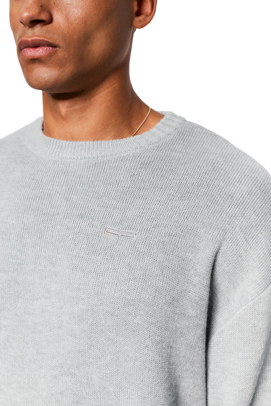 Male model wears Exquisite Knit Sweater Gray with embroidered OLAKALA logo on the chest, different knit patterns on collar and cuffs, unisex.