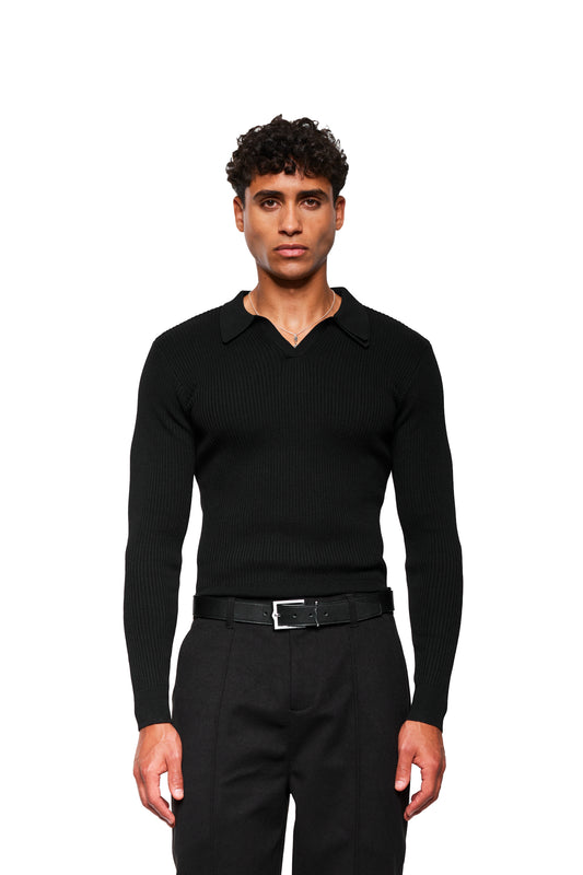 Junger Mann trägt Exquisite Rib Knit Polo Black mit V-Ausschnitt und Polo-Kragen, kombiniert mit schwarzen Hosen und einem silbernen Kettenanhänger, posiert neutral.