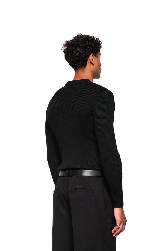 A man wears the Exquisite Rib Knit Polo Black with polo collar, close fit and cropped cuffs, photographed from behind in profile view.