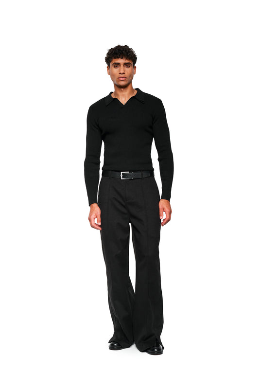 A young man wears the Exquisite Rib Knit Polo Black with double collar and tight fit, combined with high-cut black pants and elegant shoes.