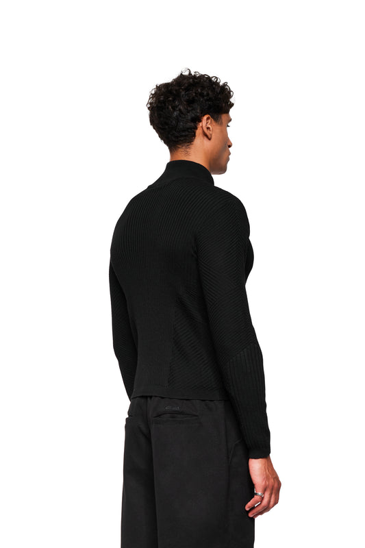 Person from behind in an Exquisite Knit Jacket Black: body-hugging knit pattern, knitted cuffs, stand-up collar. Tight fit, unisex.