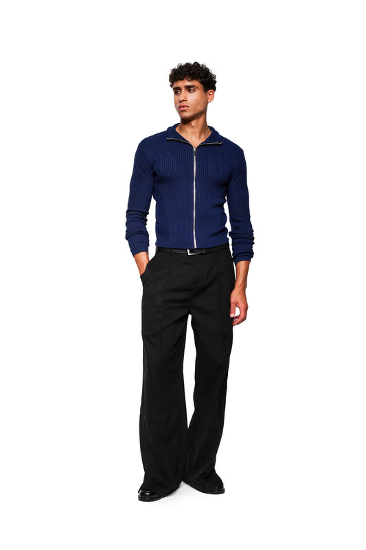 Young man in navy blue Exquisite Knit Jacket with zipper, body-hugging knit pattern and stand-up collar, combined with black, wide-cut pants.