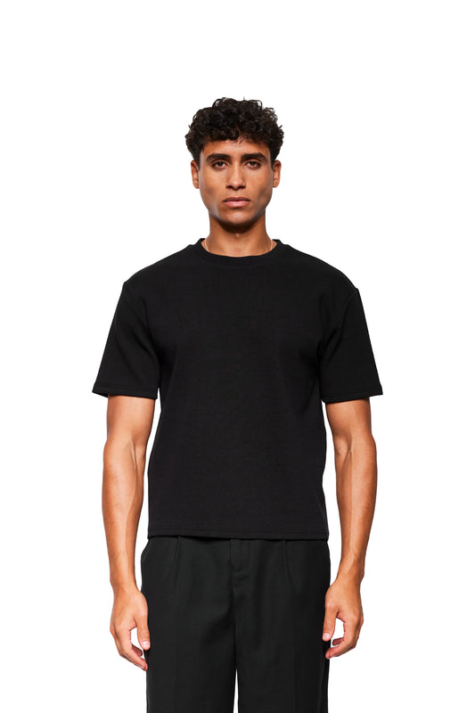Junger Mann trägt Exquisite Rib T-Shirt Black, locker geschnitten aus festem Rippstoff, präsentiert im OLAKALA® Onlineshop.