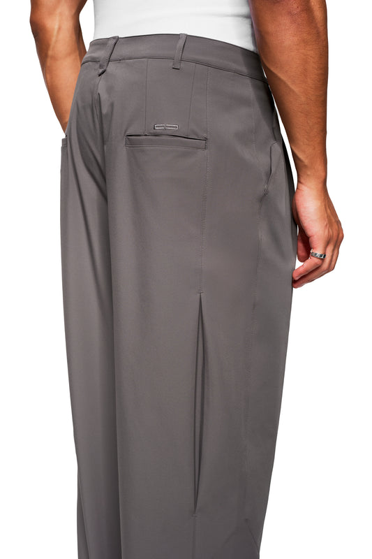 Model wears Exquisite Tech Pants Gray with loose fit, one-sided back pocket, side box pleat, robust fabric, tucked-in white tank top and plain ring.
