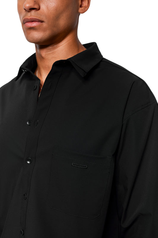 Man wears Exquisite Tech Shirt Black with double collar, breast pocket with OLAKALA embroidery, rounded hem and removable collar inserts.