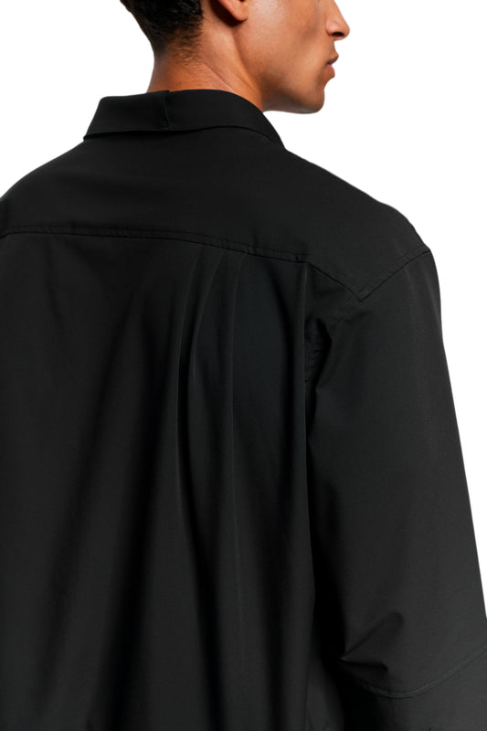 Close-up of the Exquisite Tech Shirt Black with double collar, pleats on the back yoke and OLAKALA icon embroidery, worn by one person.