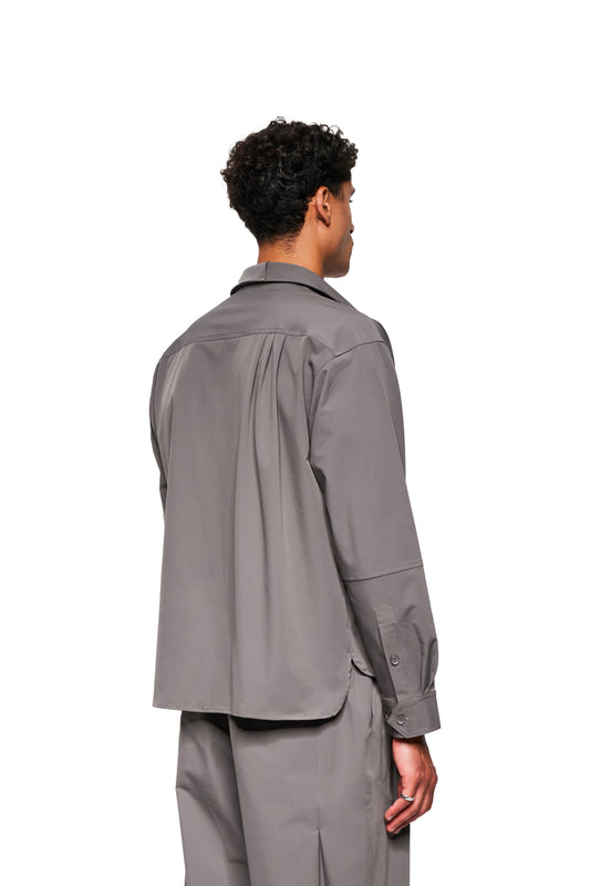 Person from behind in the Exquisite Tech Shirt Gray with double collar, breast pocket with embroidery, loose fit and rounded hem, matching gray trousers.