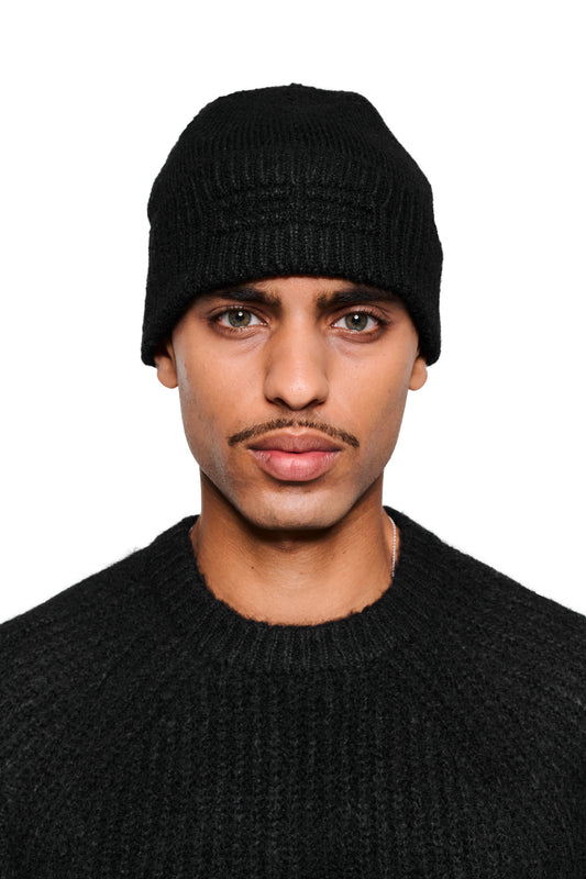 Junger Mann trägt die Fuzzy Beanie Black mit breitem Umschlag und dezentem Logo, ideal für kalte Tage, aus dem offiziellen OLAKALA® Onlineshop.
