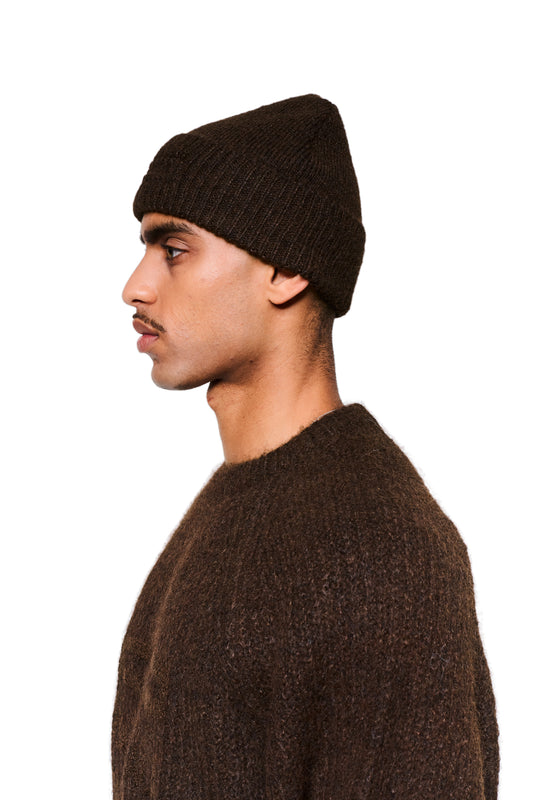 Junger Mann mit Fuzzy Beanie Brown in Seitenansicht, breiter Umschlag mit dezentem Logo, passend zum strukturierten Pullover.