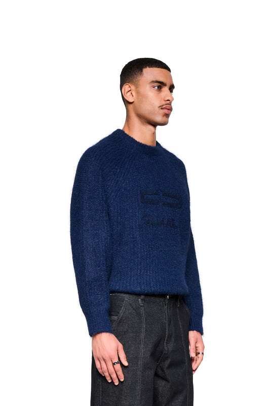 Men's Fuzzy Knit Sweater in Navy Blue with a cropped, boxy silhouette and large embroidered logo, paired with dark jeans.